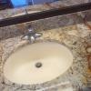 Bathroom vanity w/ granite top and oval sink.